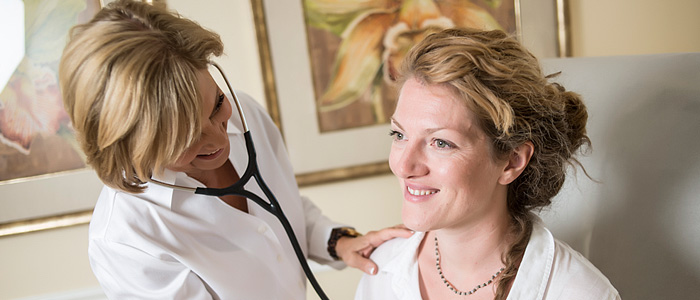 Dr. Britten listening to a patient’s heart during an annual wellness exam